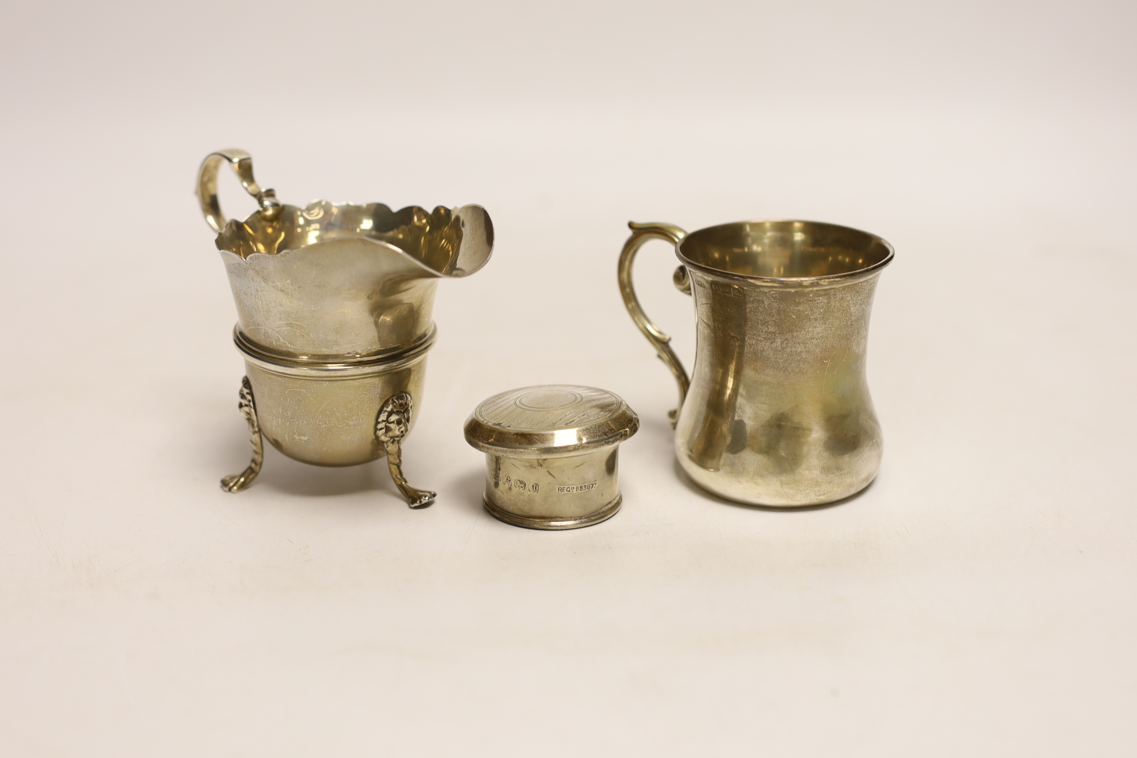 A George V silver cream jug, Goldsmiths & Silversmiths Co Ltd, London, 1921, 82mm, a small silver mug and a silver scent bottle top.